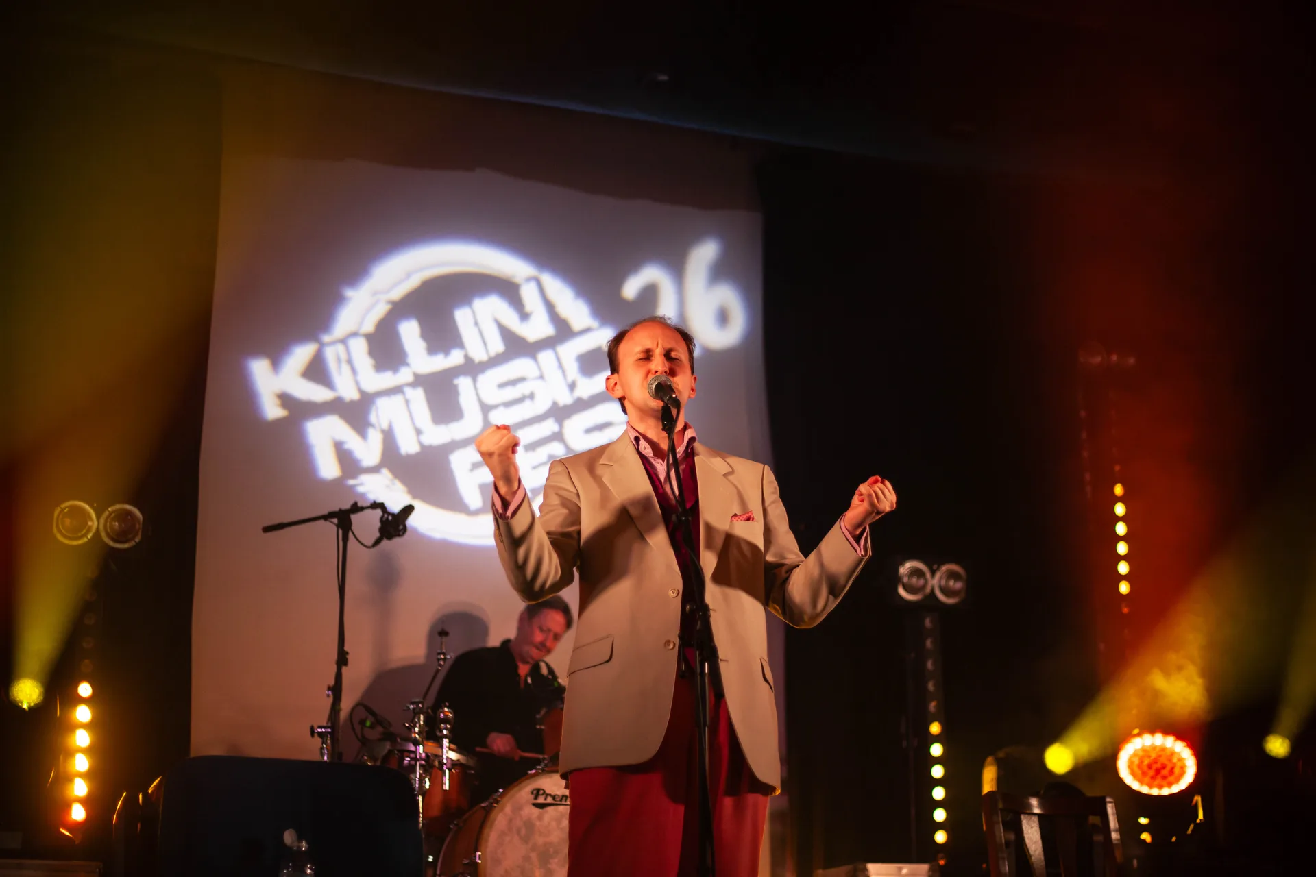 Singer performing with eyes closed in front of the festival logo