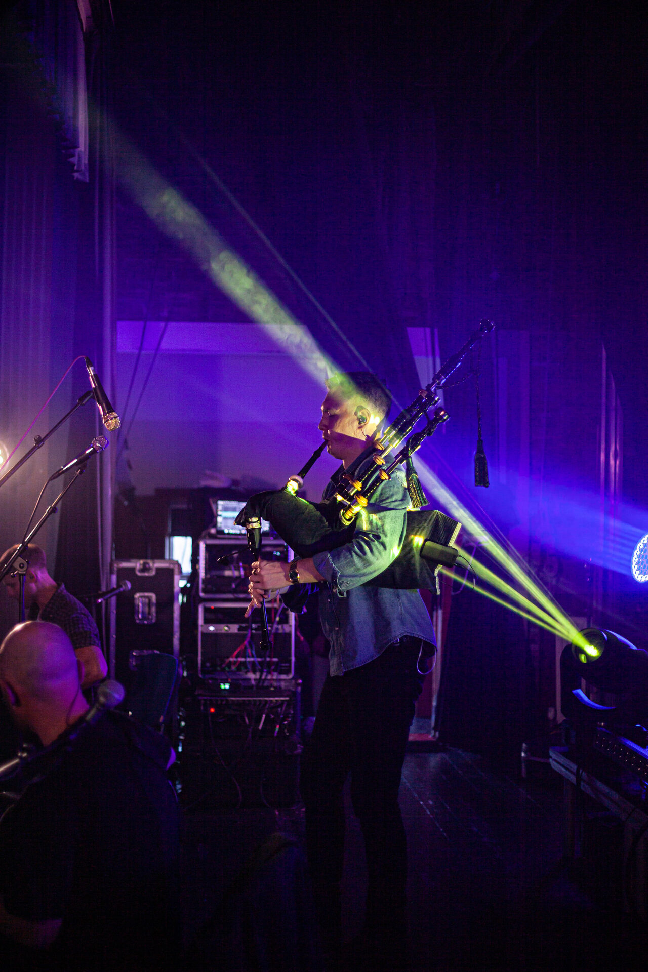 Piper performing in profile as a green beam cuts through the haze