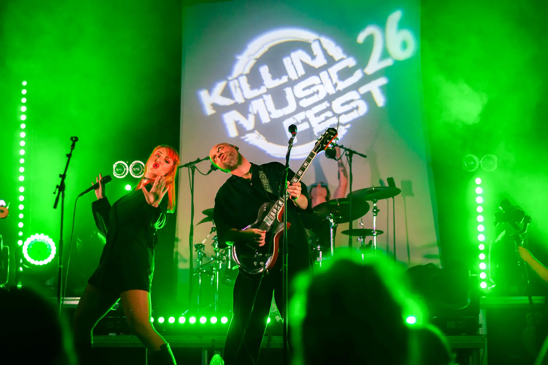 Five-piece band performing under green stage light