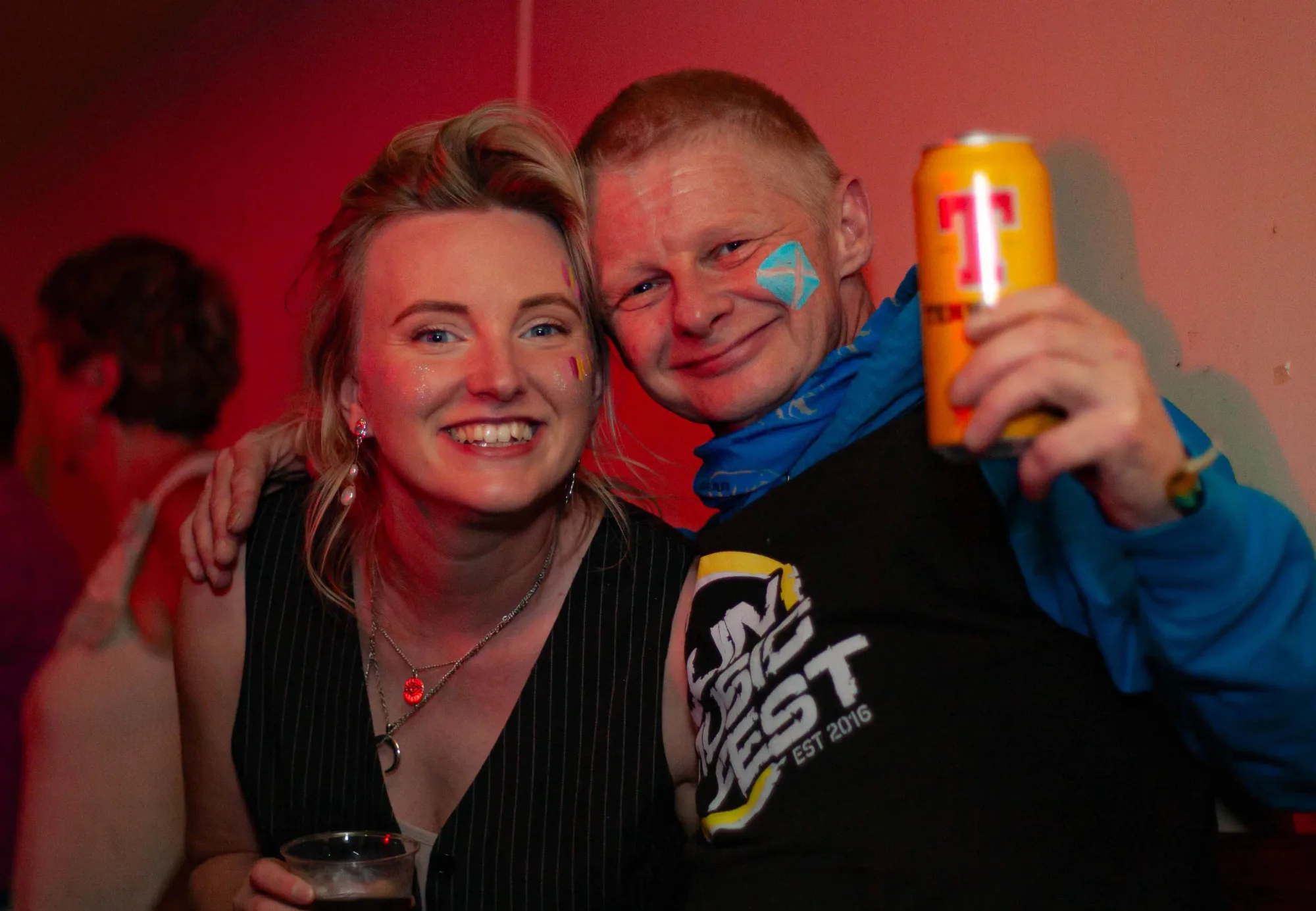 Two festival-goers with face paint sharing a laugh in the bar